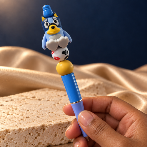 Blue puppy beaded pen held in hand, showing its white paw-print bead, yellow accent, and glossy blue barrel
