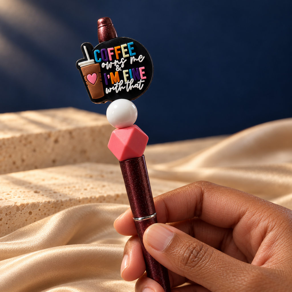 Coffee Mood burgundy glitter-look pen held in hand, with coffee quote charm, glossy white bead, and pink hexagonal bead