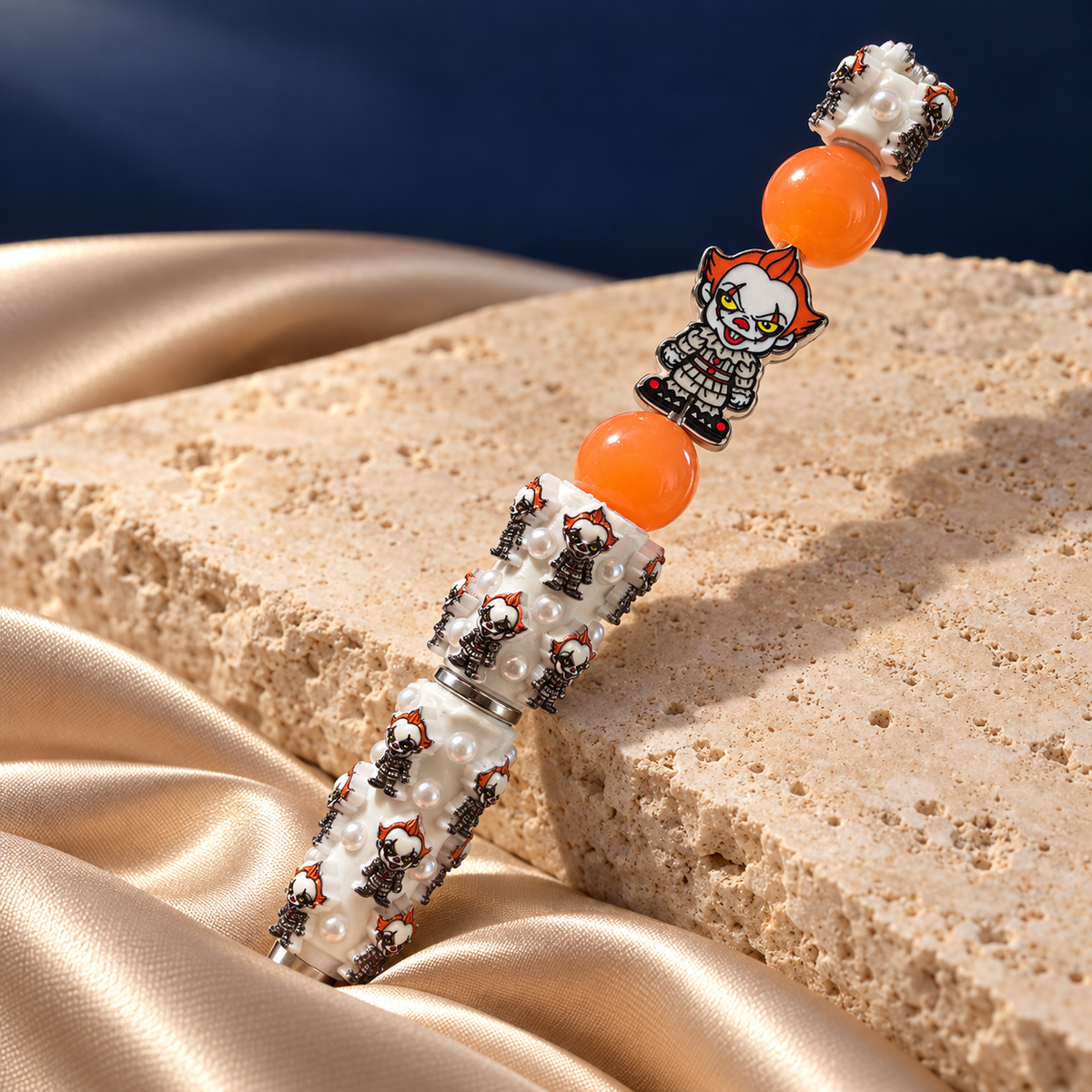 Angled view of Midnight Carnival Beaded Pen showing its white decorated barrel, orange beads, and miniature clown details