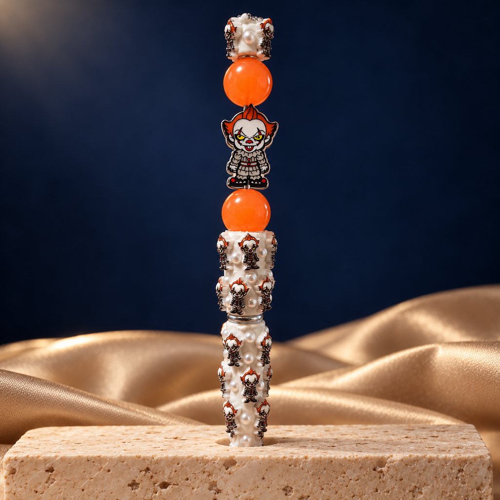 Midnight Carnival Beaded Pen standing upright with orange beads, a spooky clown focal piece, and white pearl-look detailing