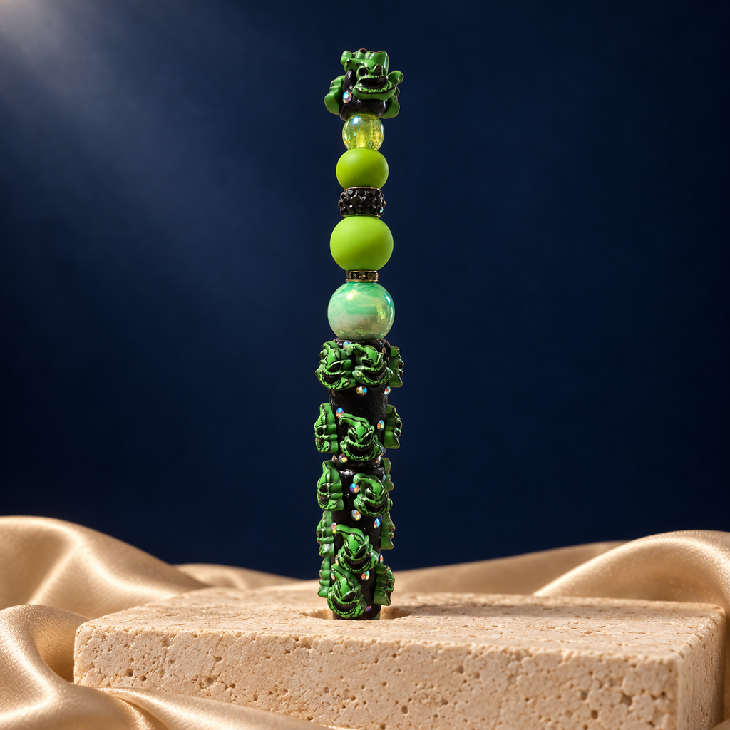 Black decorative pen covered in green grinning character details, with lime beads, iridescent accents, and matching green topper
