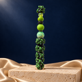 Black decorative pen covered in green grinning character details, with lime beads, iridescent accents, and matching green topper