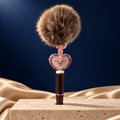 Brown glitter-look pen with brown pom-pom, pink accents, and a cream heart charm with floral border and Prada lettering